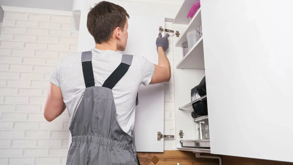 Monteur arbeitet an einem Küchenschrank bei der professionellen Möbelmontage nach einem Umzug.